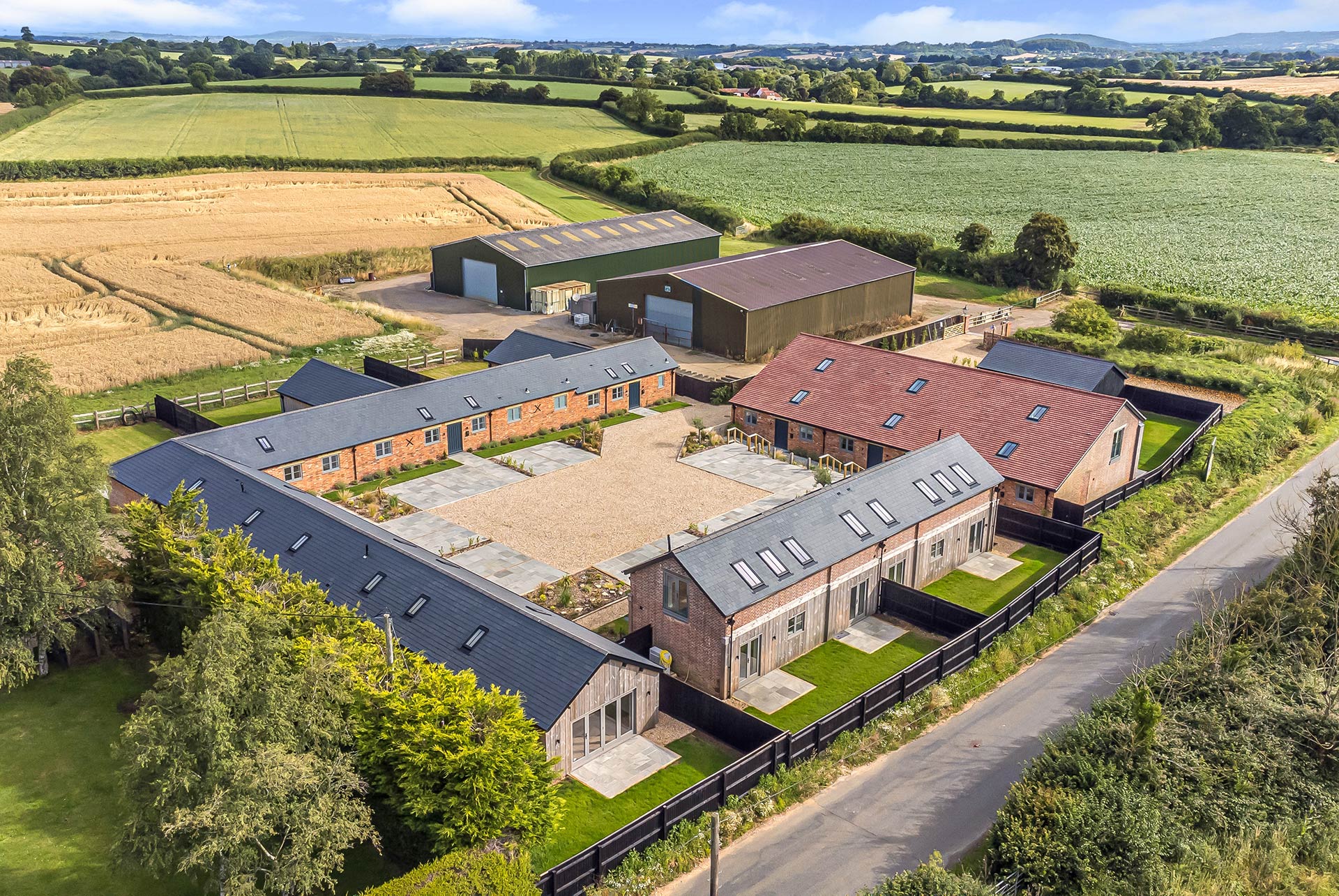 aerial view of farmhouse with courtyard and outbuildings surrounded by countryside