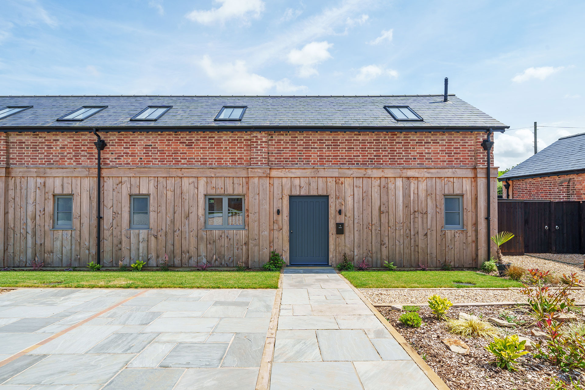 finished photo of converted barn with red brick and timber clad