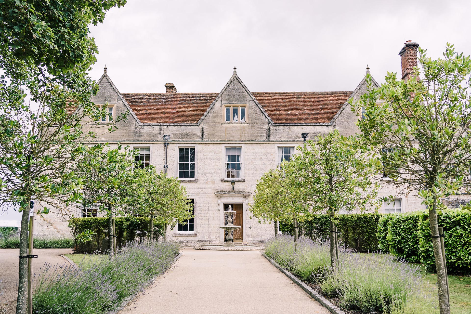 approach to large county house with tree lines walkway to entrance