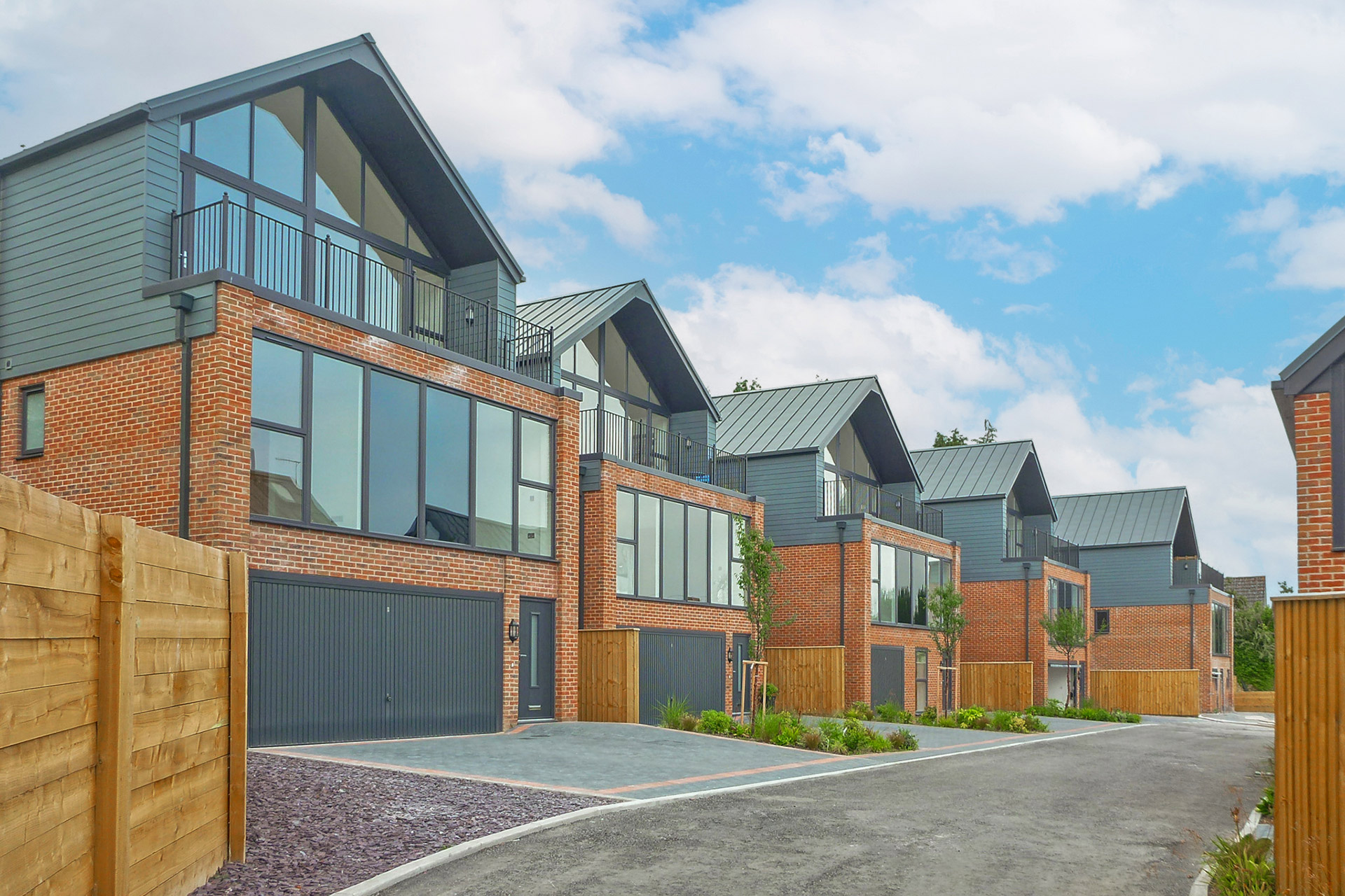 street view of modern red brick houses with zinc cladding and large driveways