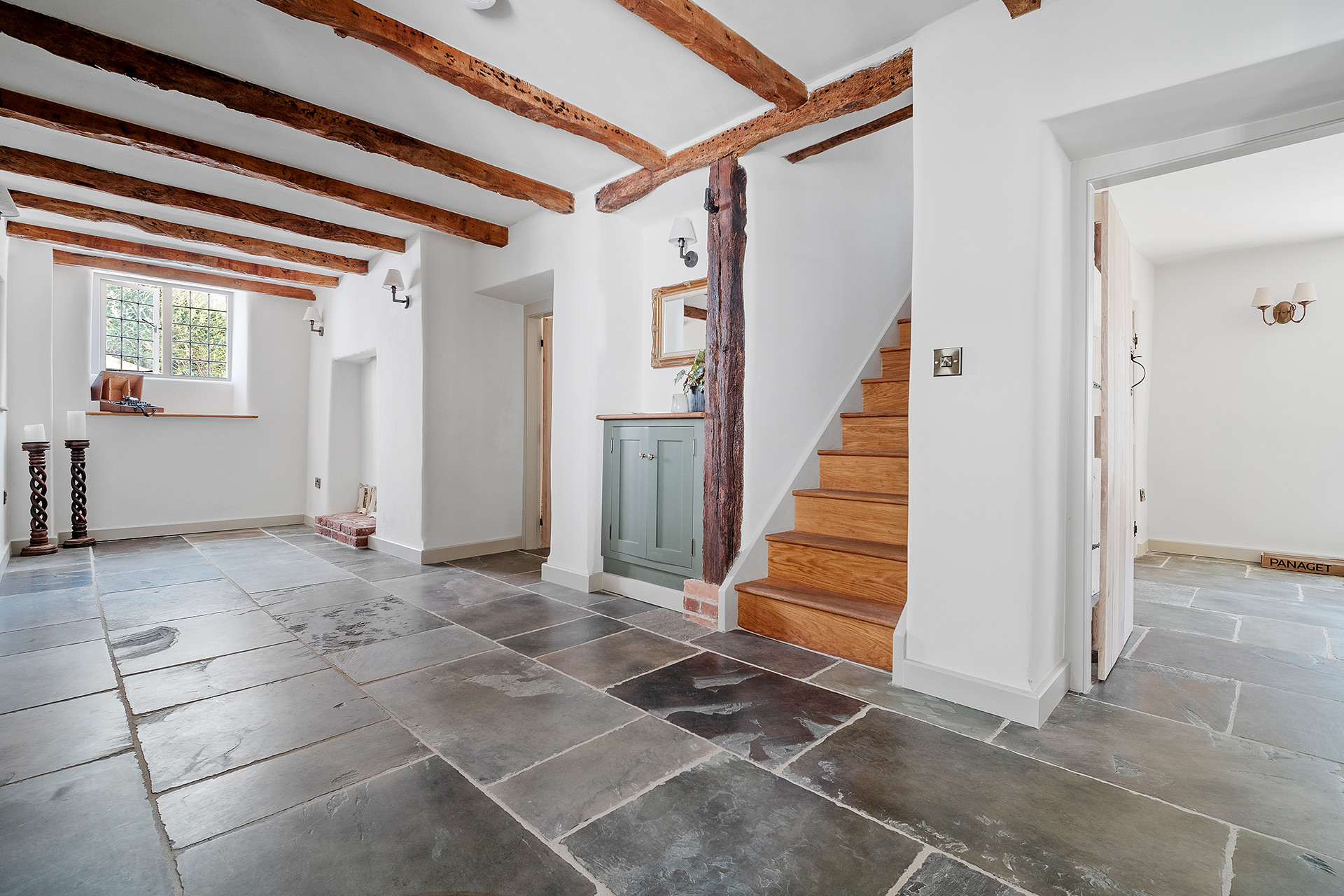 traditional living space with exposed beams, wooden staircase and flagstone floors