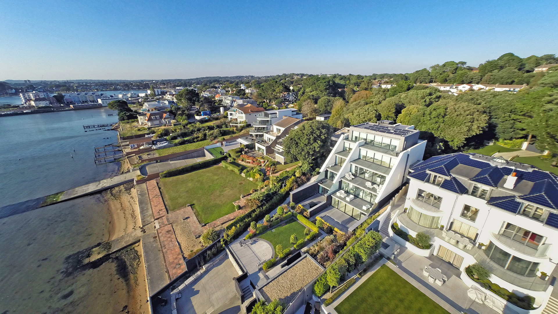 aerial view of large modern properties with gardens backing onto the seafront