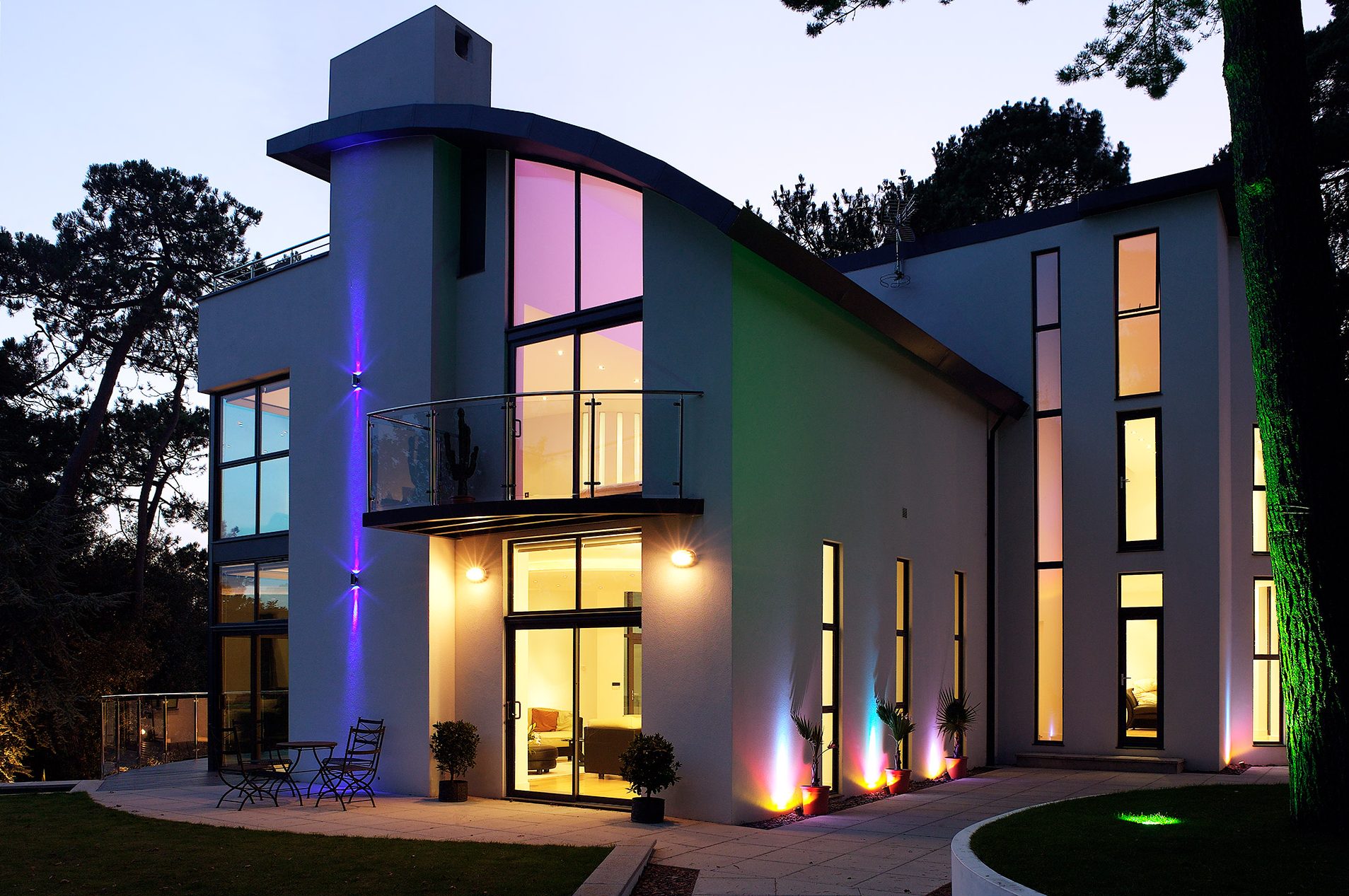 front view of house with curved roof feature at dusk with lights on