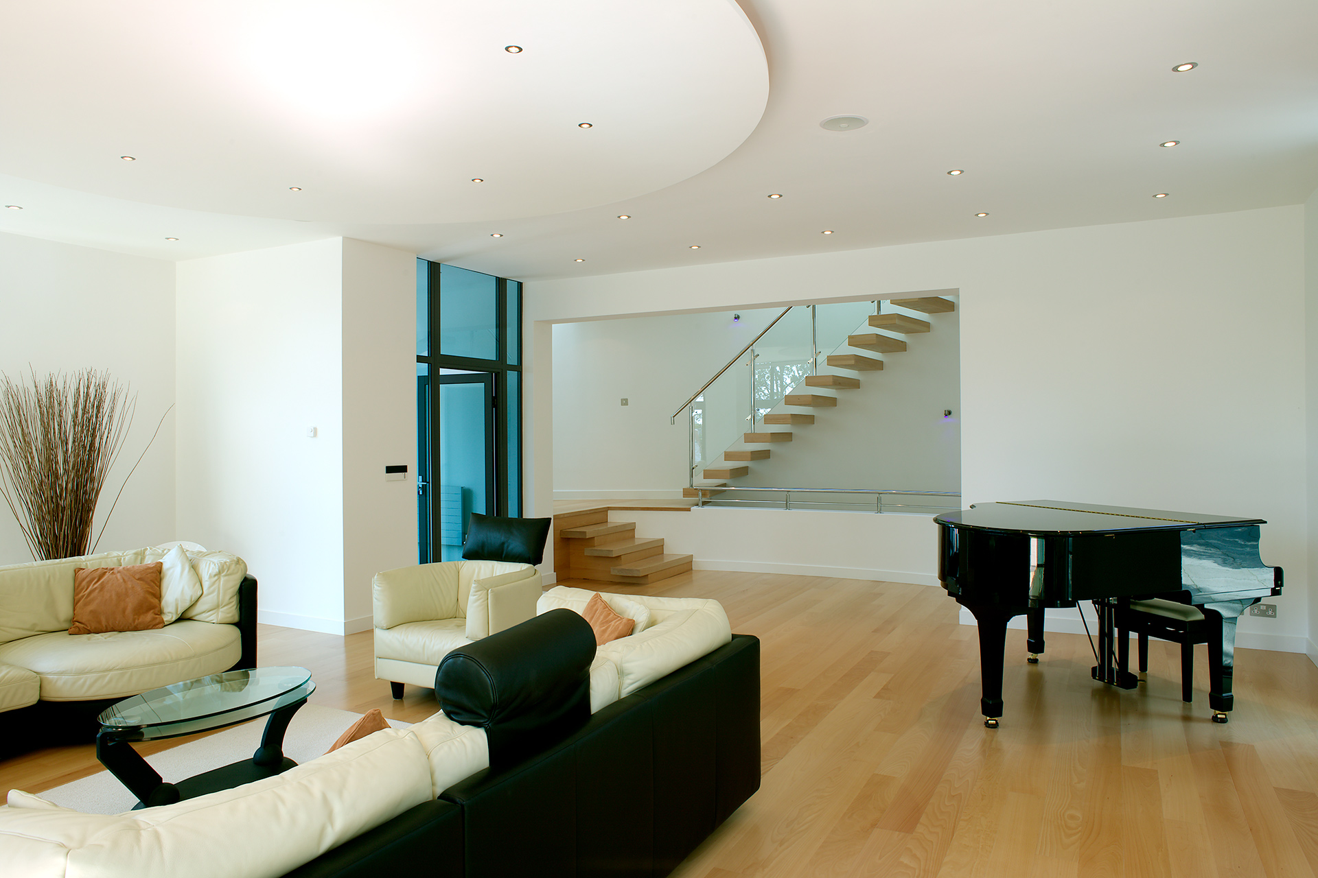 interior modern open plan living space in black and white tones with grand piano and floating staircase