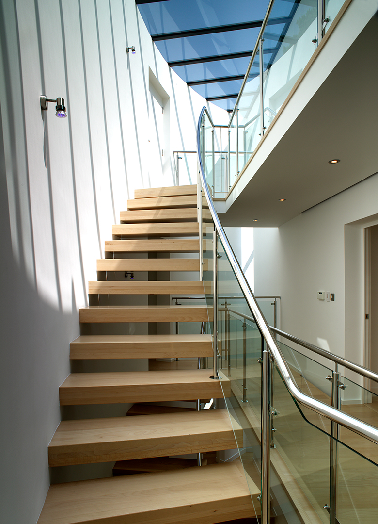 open tread wooden staircase with glass balustrade and glass sky lights ceiling