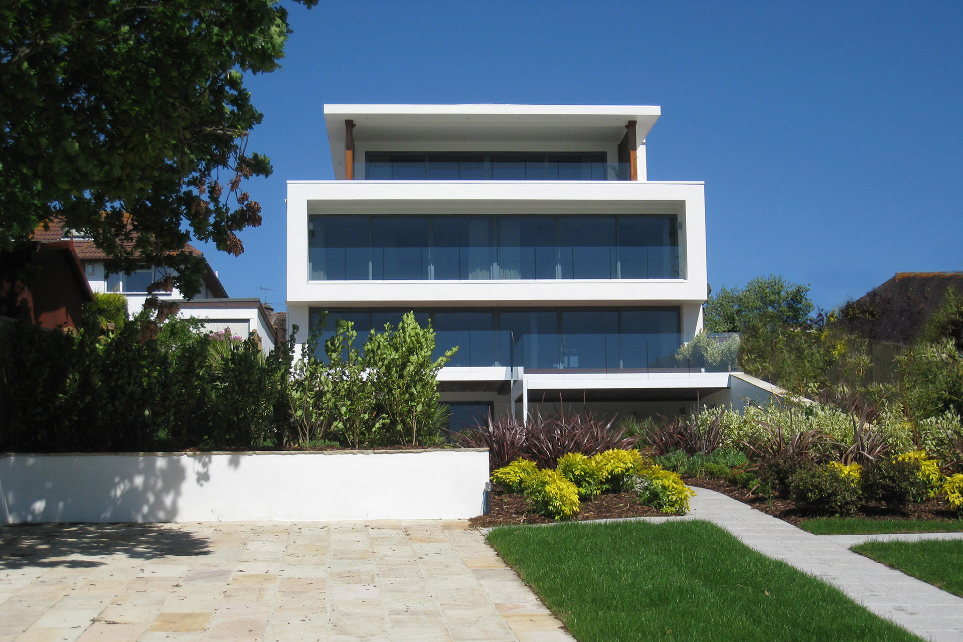 view of contemporary white house from garden with balconies