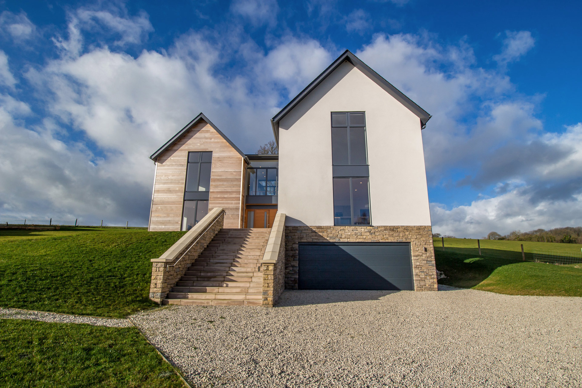 front view of modern house with stone stairs leading to house and garage under house