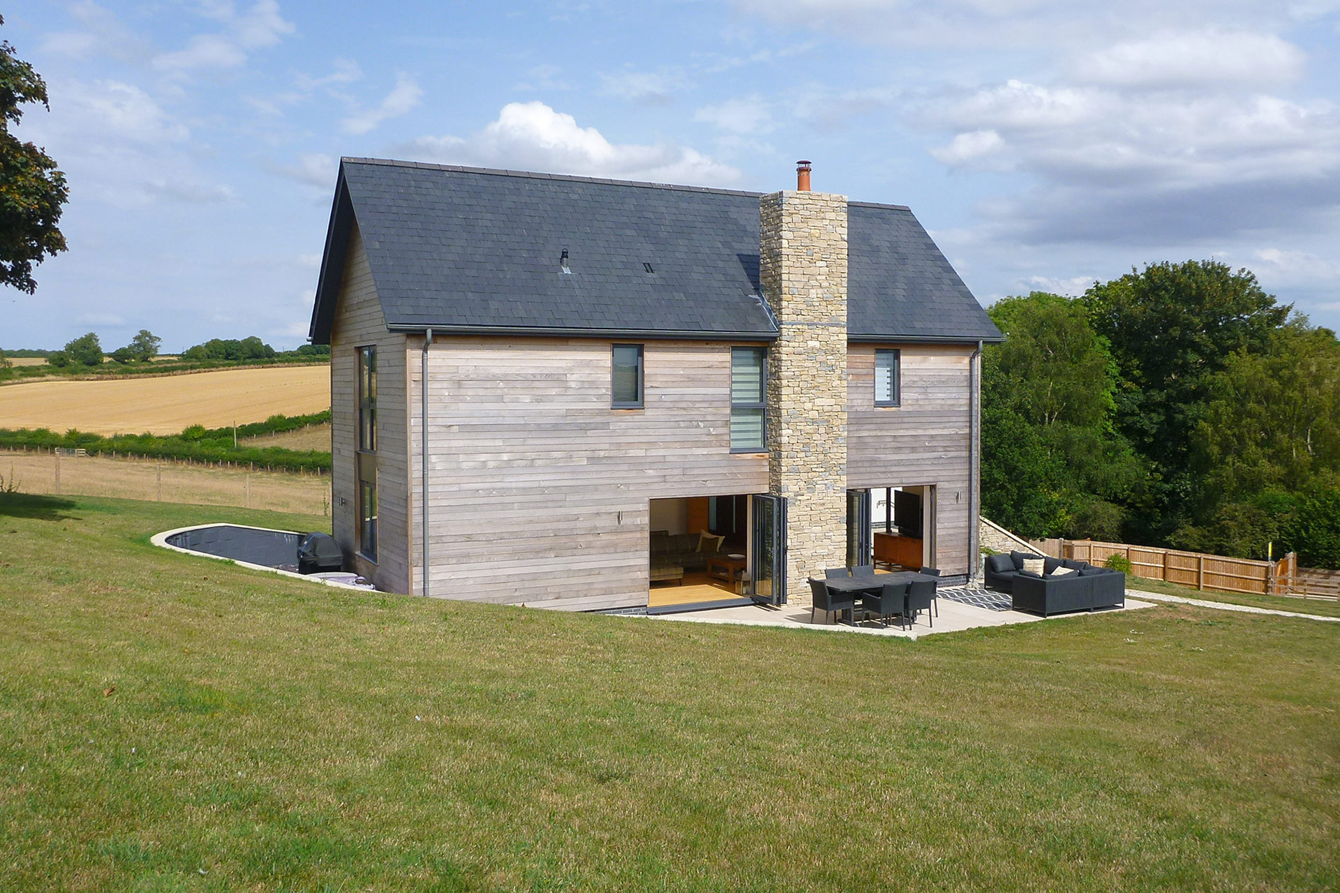 side view of contemporary house with stone chimney and timber cladded walls