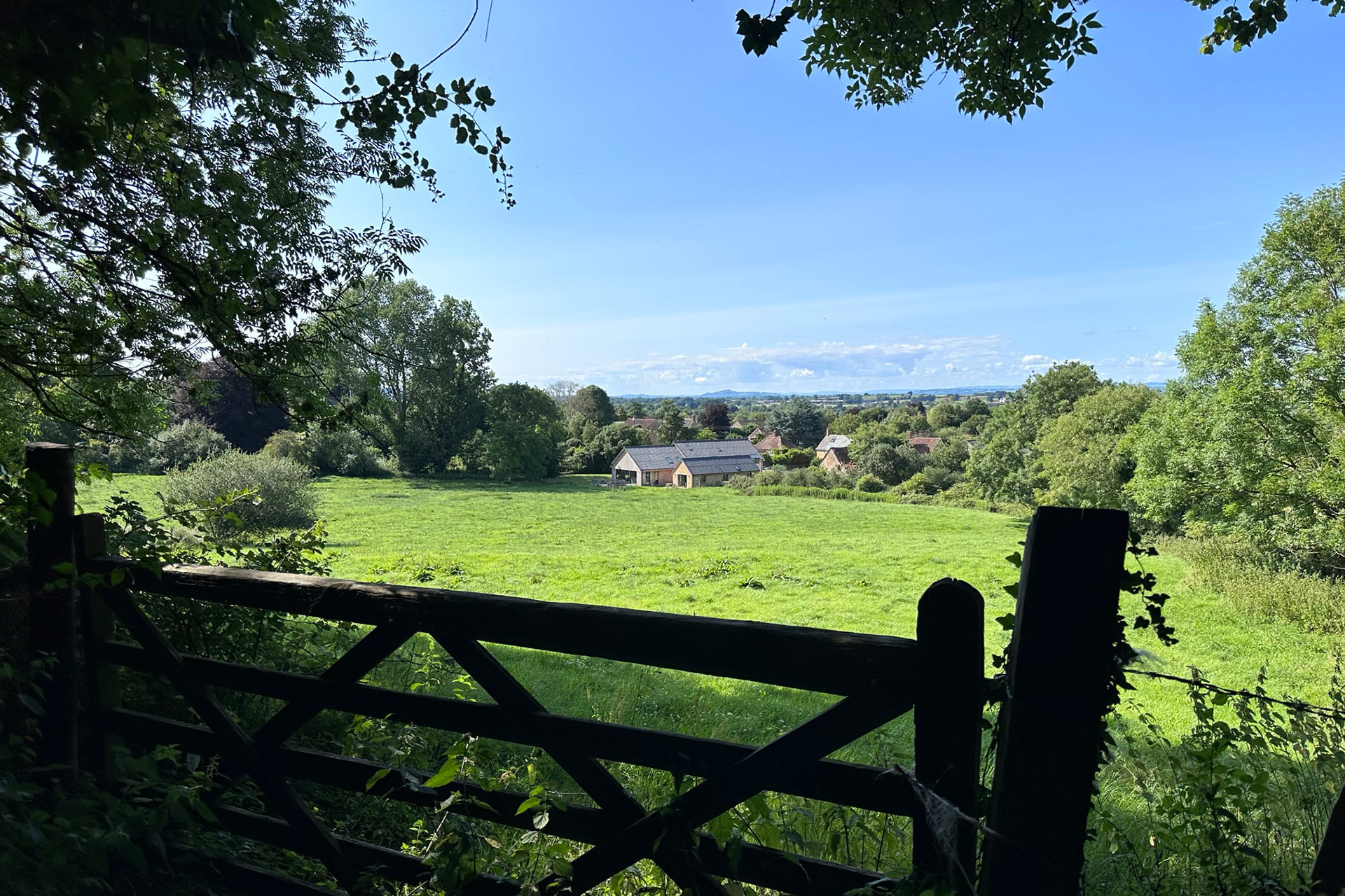 barn conversion taken across field behind wooden gate