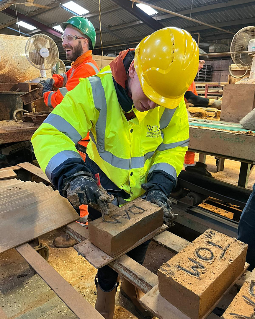 man carving name in handmade brick