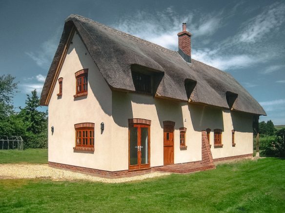 detached white thatched house with brick chimney