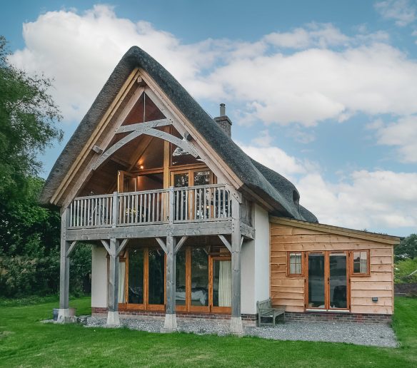 detached thatched house with beautiful wood balcony extension