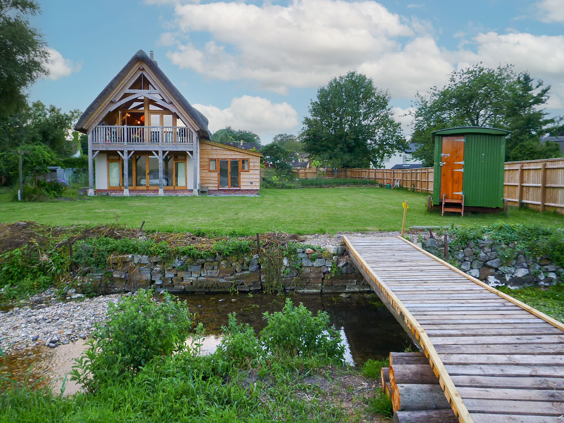 garden view of beautiful thatch house with bridge over river in garden