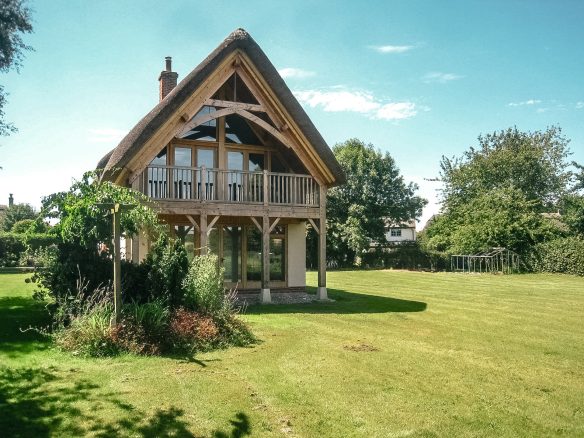 detached thatched house with beautiful wood balcony extension with lawn garden surround