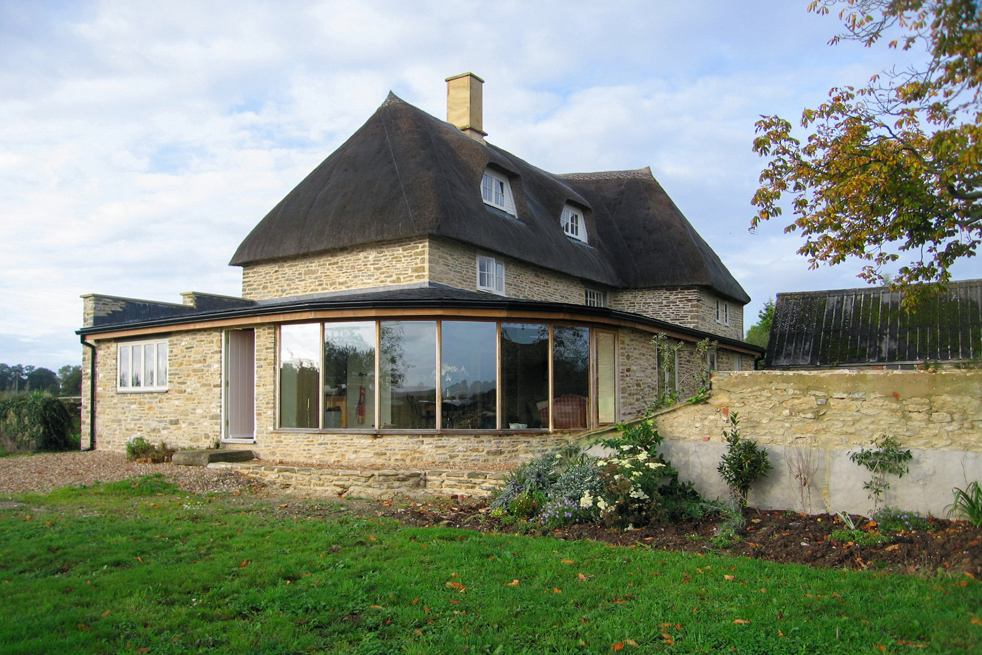 side view of curved extension with large windows and stone wall