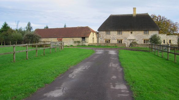 approach view of large stone thatched house with outbuildings