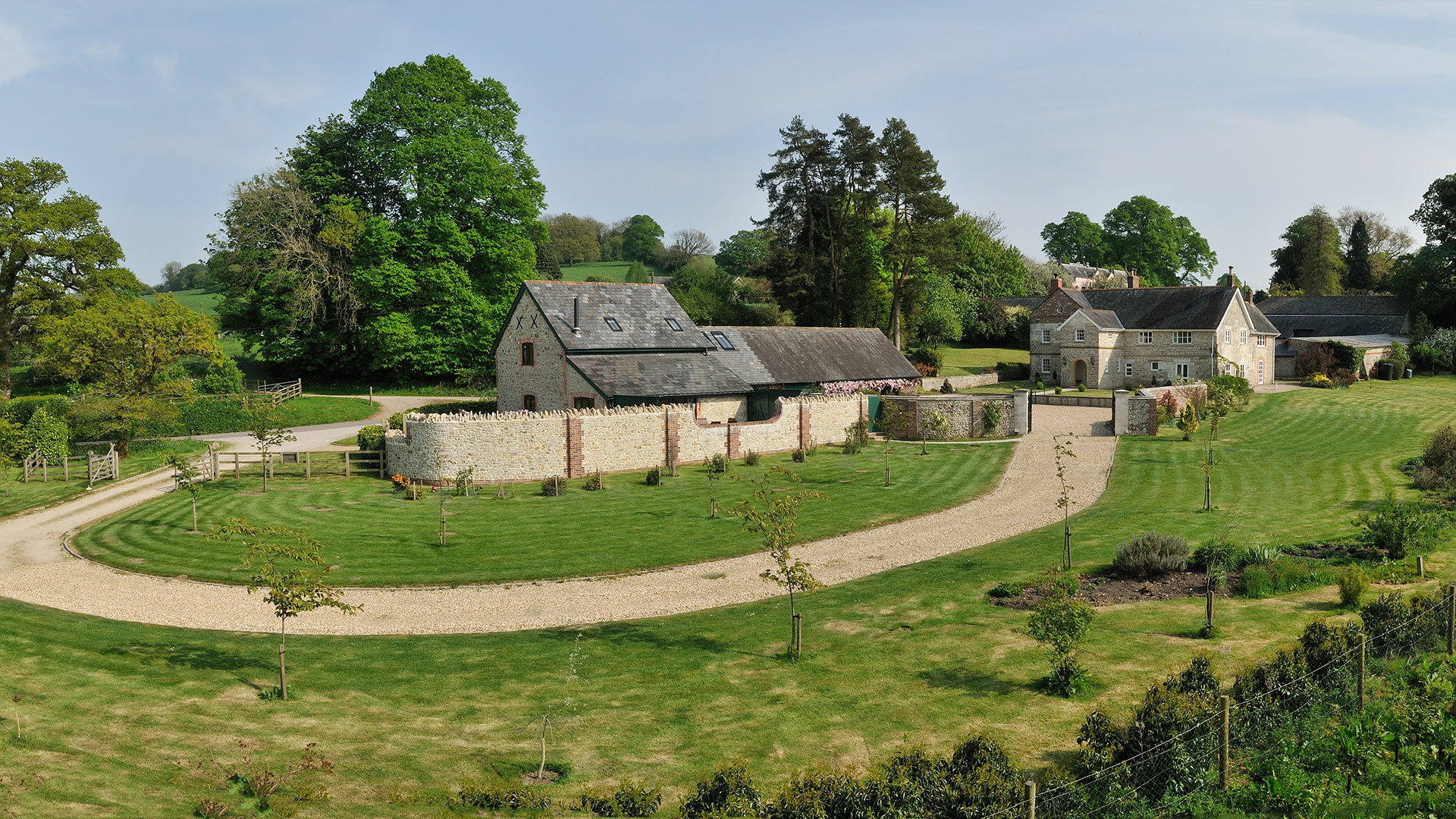 long curved driveway leading to heritage house and outbuildings with neat garden