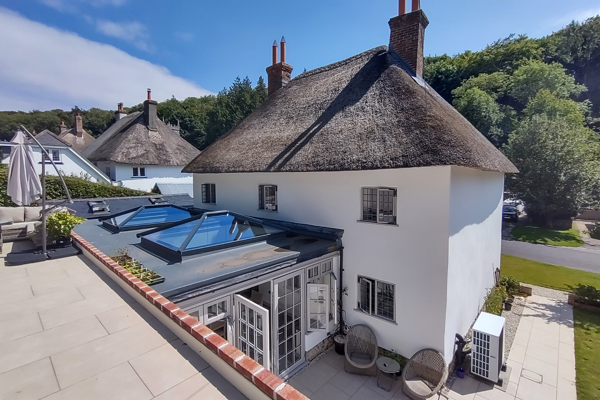 rear view of white house with extension and thatched roof