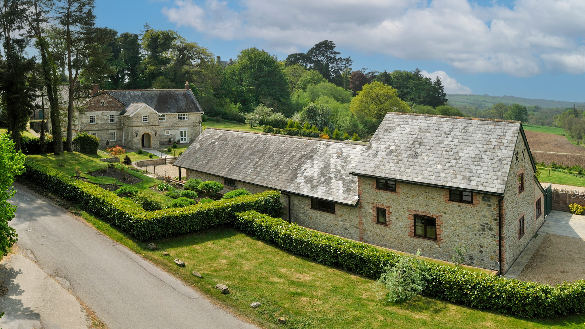 road view of house and outbuildings with countryside behind