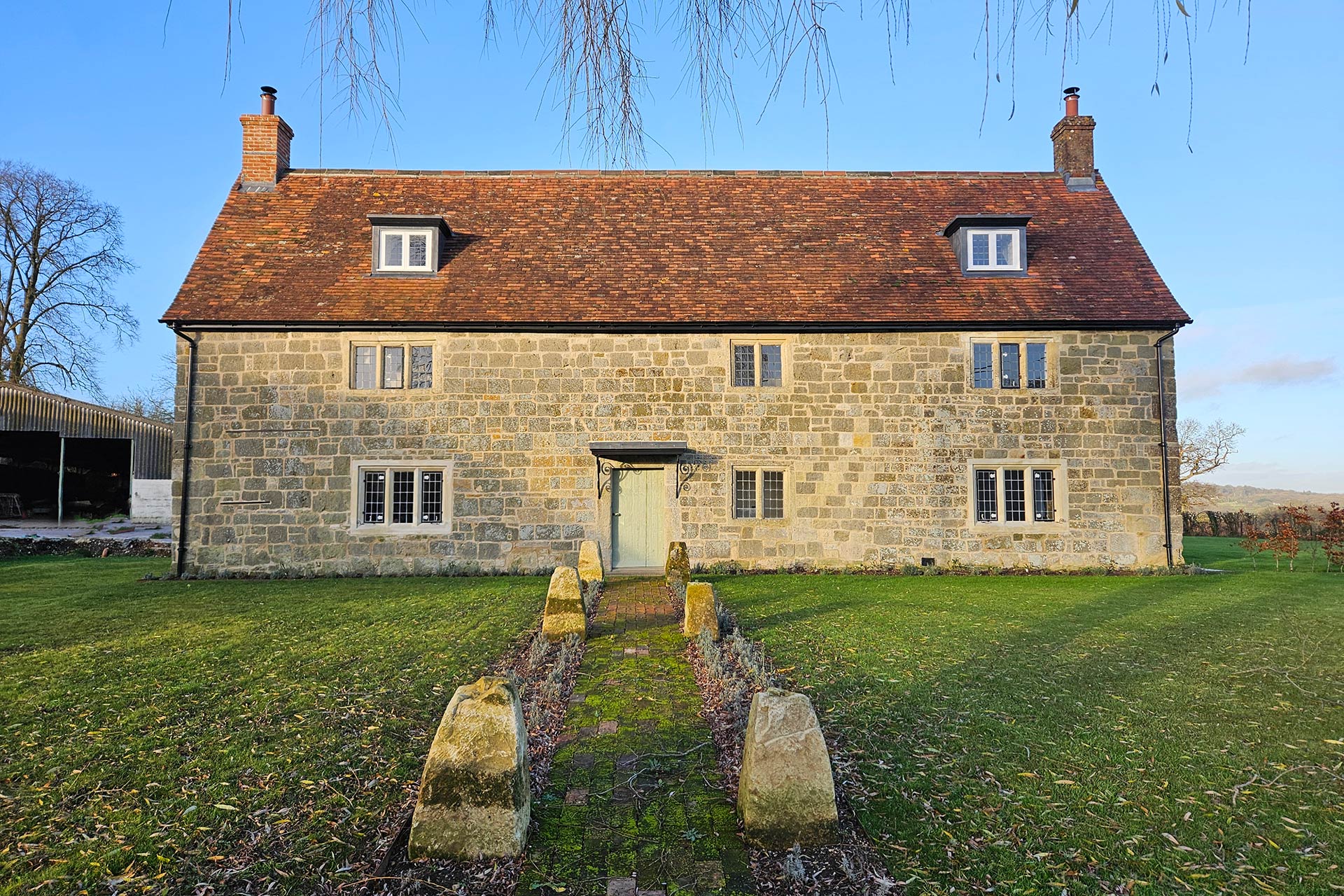 front view main elevation of stone detached house with red tiled roof