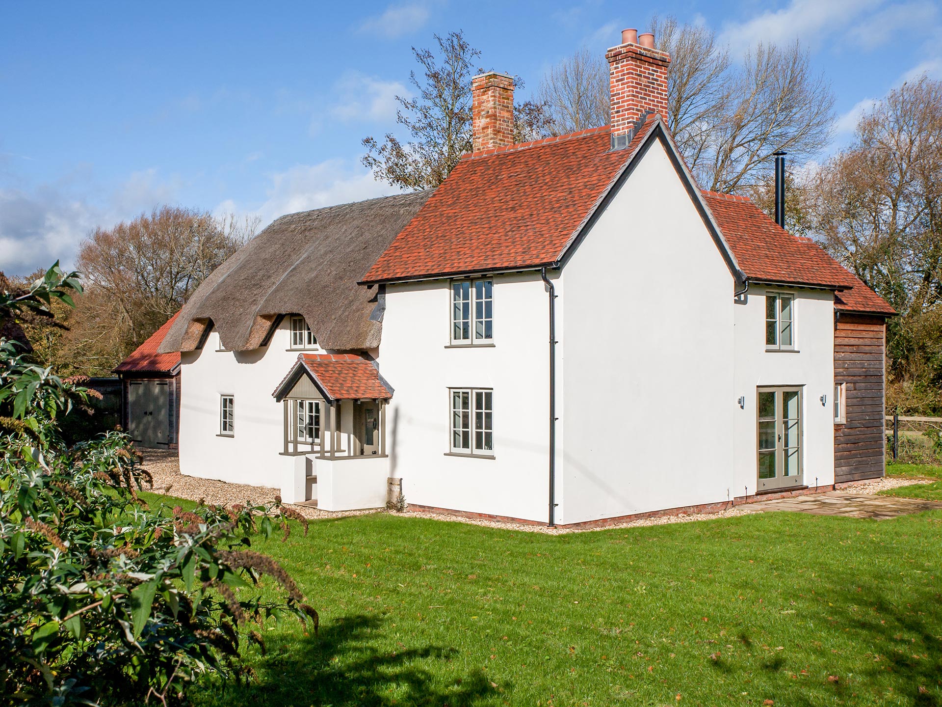 front and side view of traditional house with red tiled and thatched roof