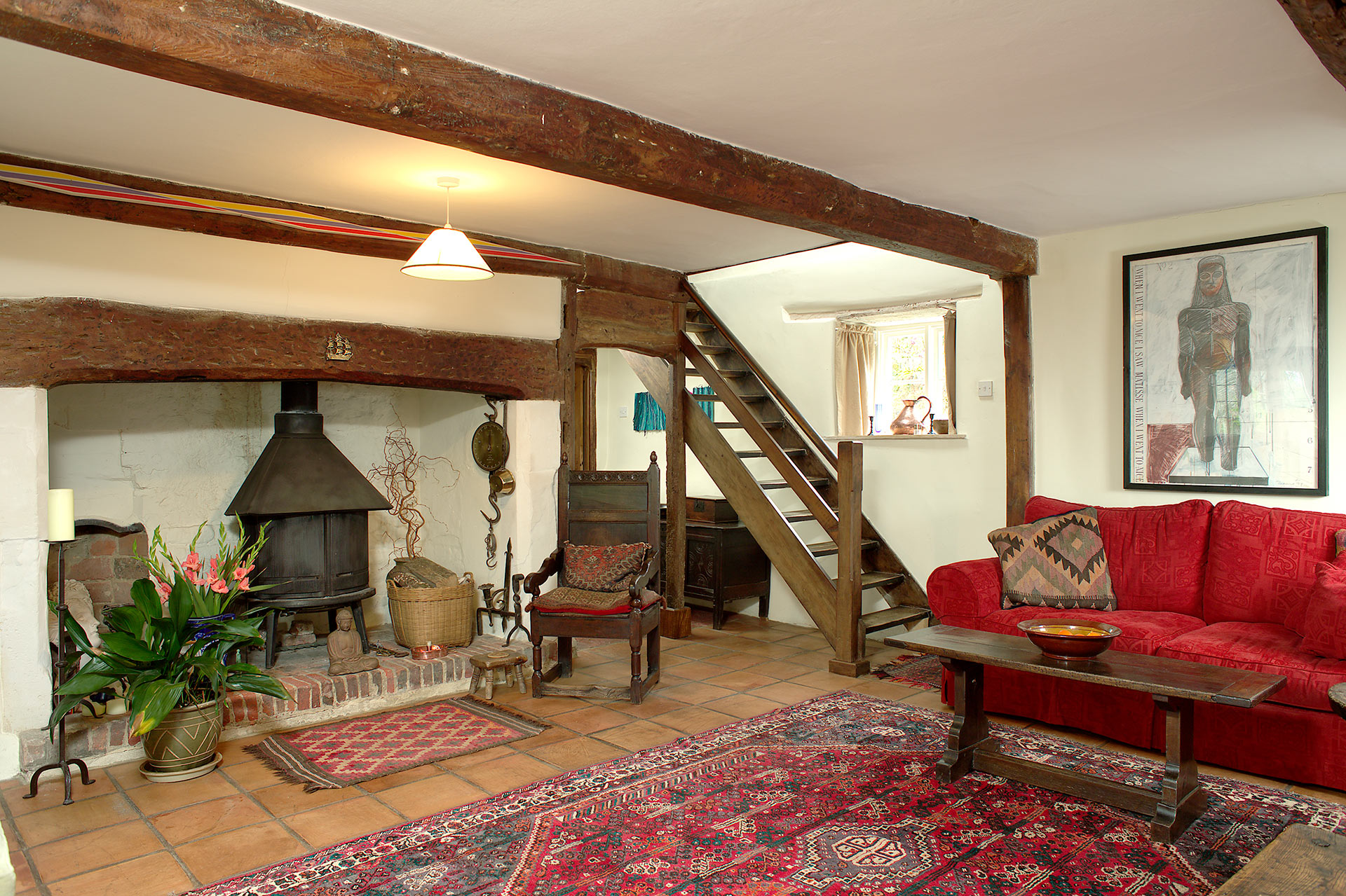 living room with exposed timber beams and large fireplace with log burning stove