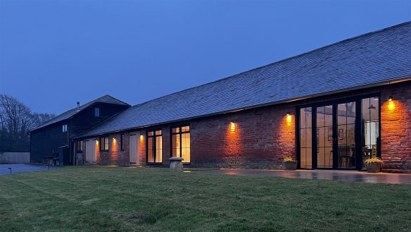 Exterior from view of red brick community building at dusk with lights on