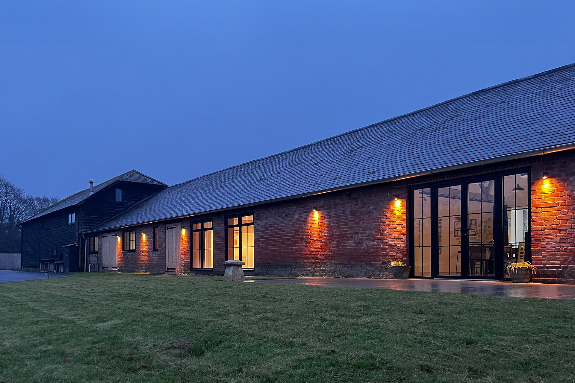 Exterior from view of red brick community building at dusk with spotlights on red brick walls