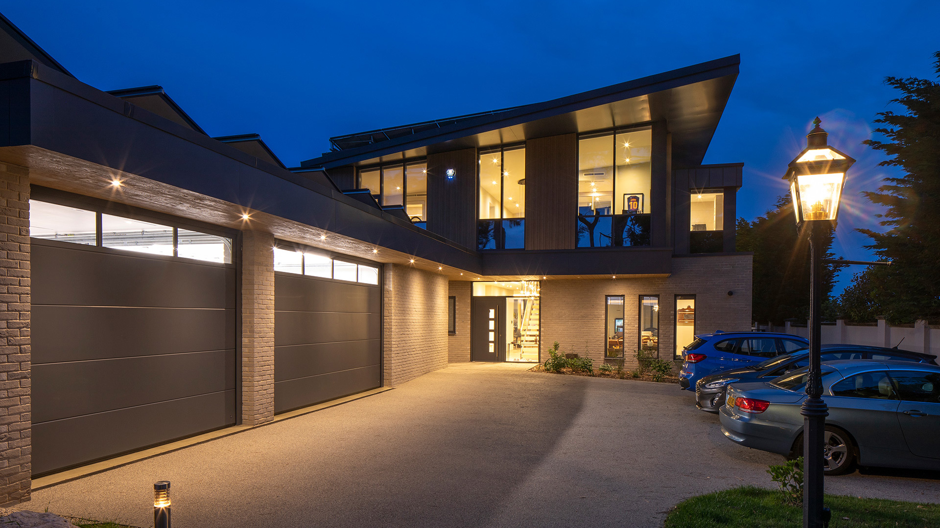 approach view to contemporary house at night with lights on