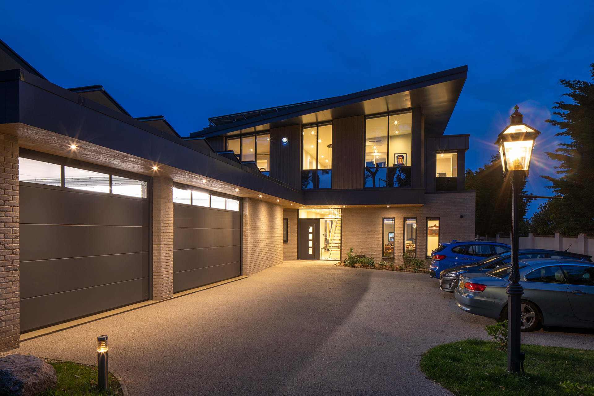 approach view to contemporary house at night with lights on