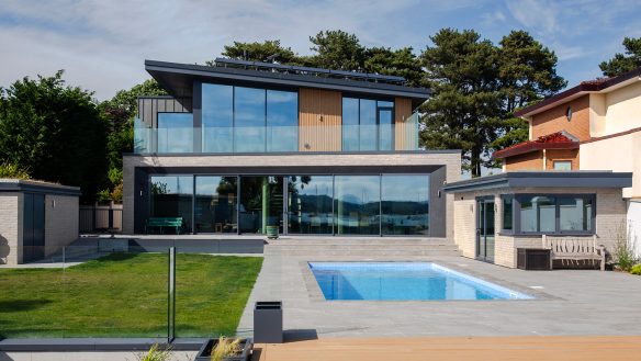 Rear garden with swimming pool and contemporary house with balcony