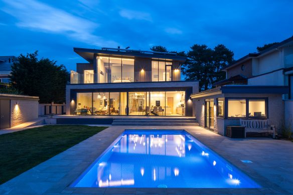 Rear view of house with swimming pool at night with lights on