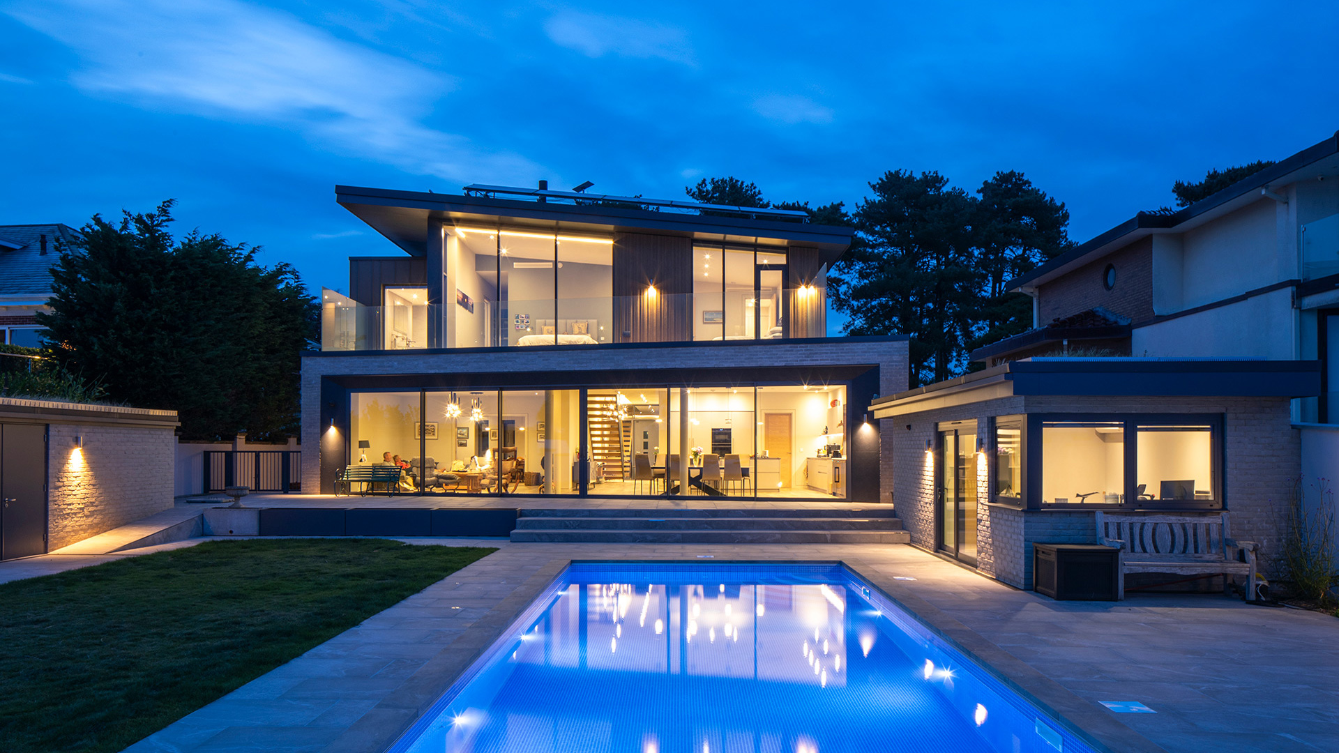Rear view of house with swimming pool at night with lights on