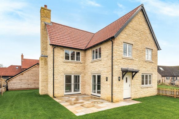 rear view of detached stone house with patio area