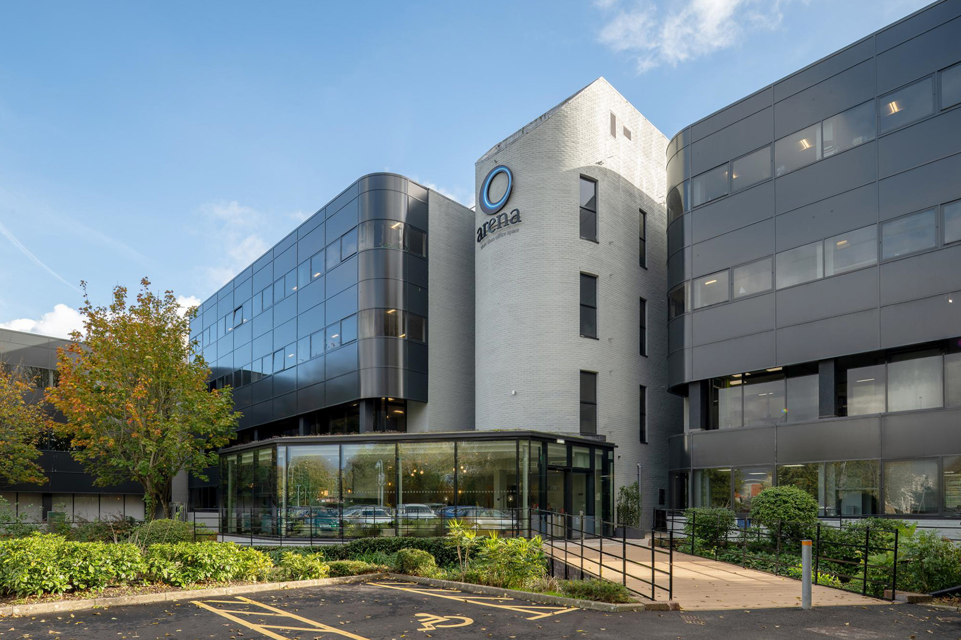 large commercial office building with black cladding and glass extension
