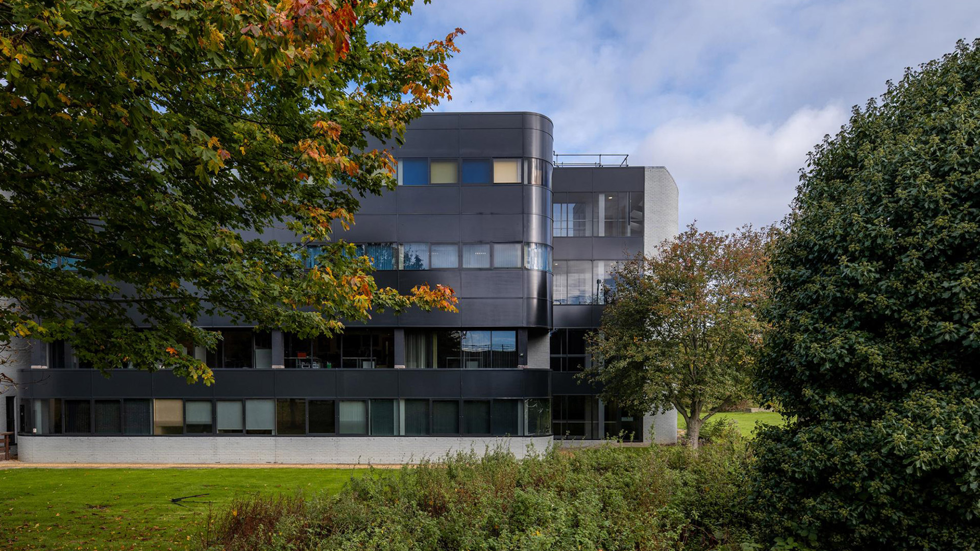 large commercial office building with black cladding and glass extension