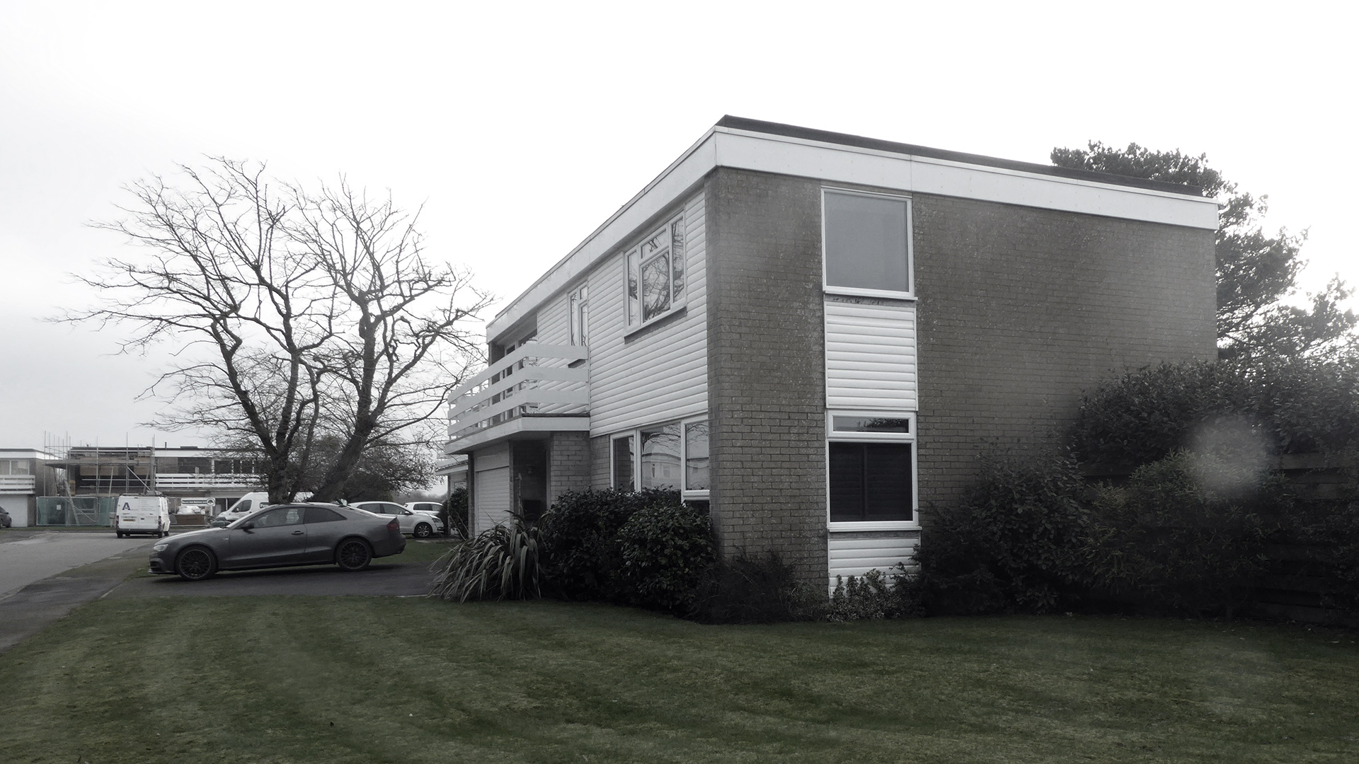 before photo of front and side view of house with flat roof and parking space in front