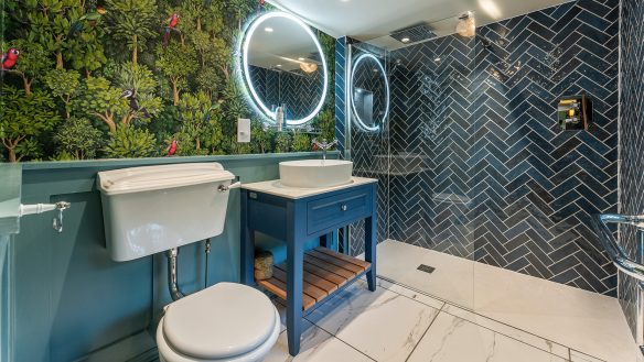 contemporary bathroom with blue tiles in shower area and tropical wallpaper