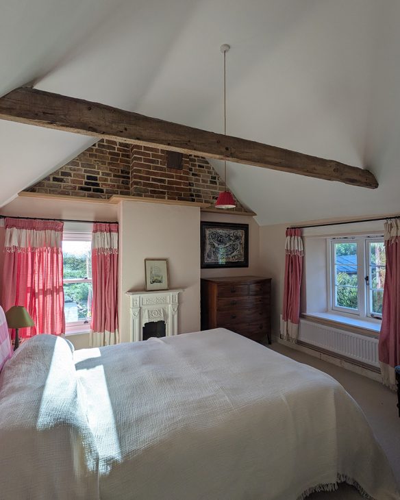 Interior bedroom with exposed brickwork on wall, vaulted ceilings and exposed timber beam