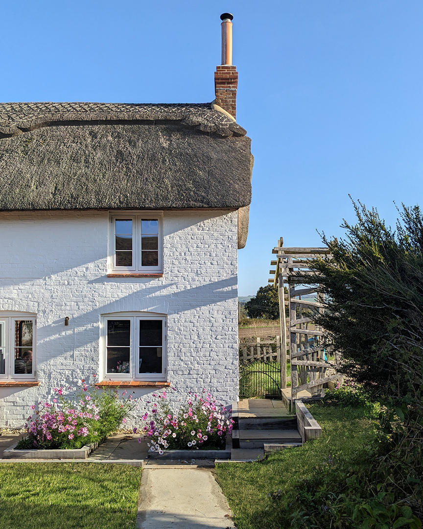 Detail rear view of thatched cottage with white brick walls