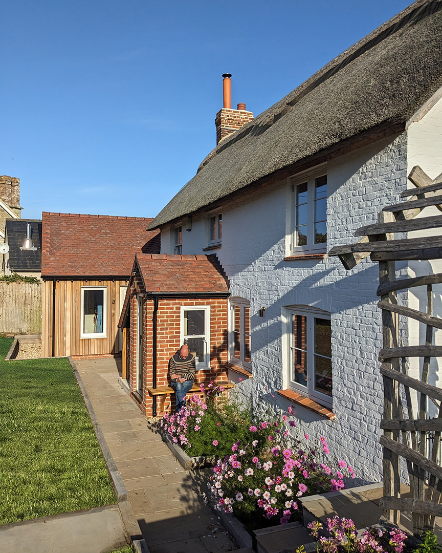 Rear view of detached thatched traditional cottage with timber extension
