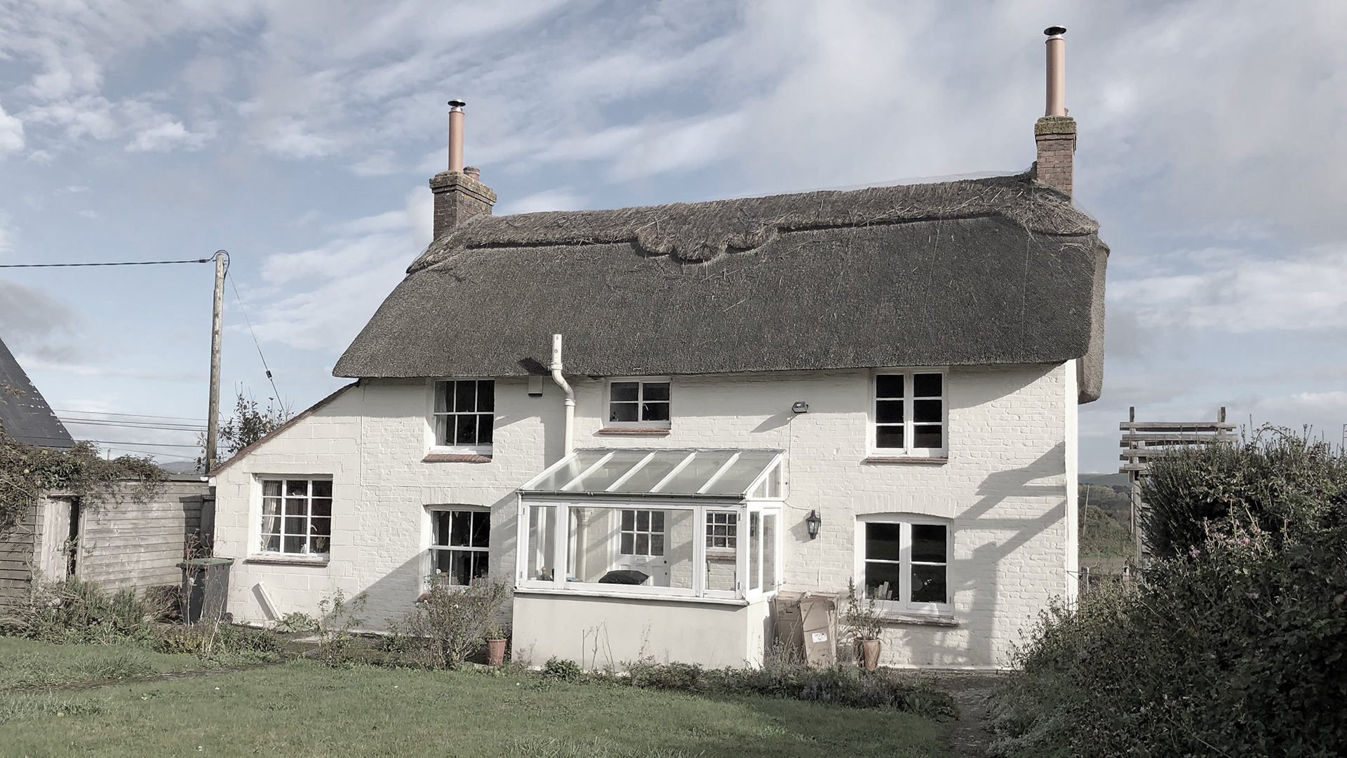 Before photo of rear view of detached thatched house
