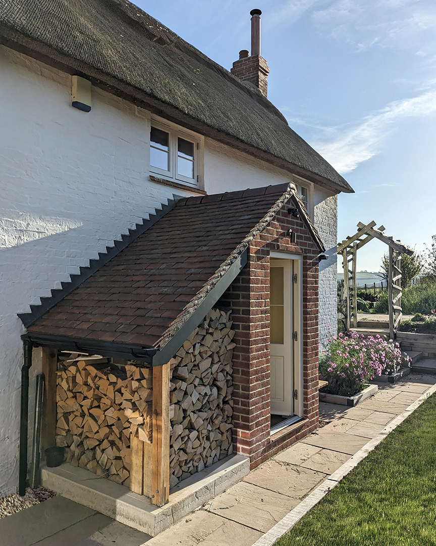 Rear brick porch with tiled roof and log store to the side