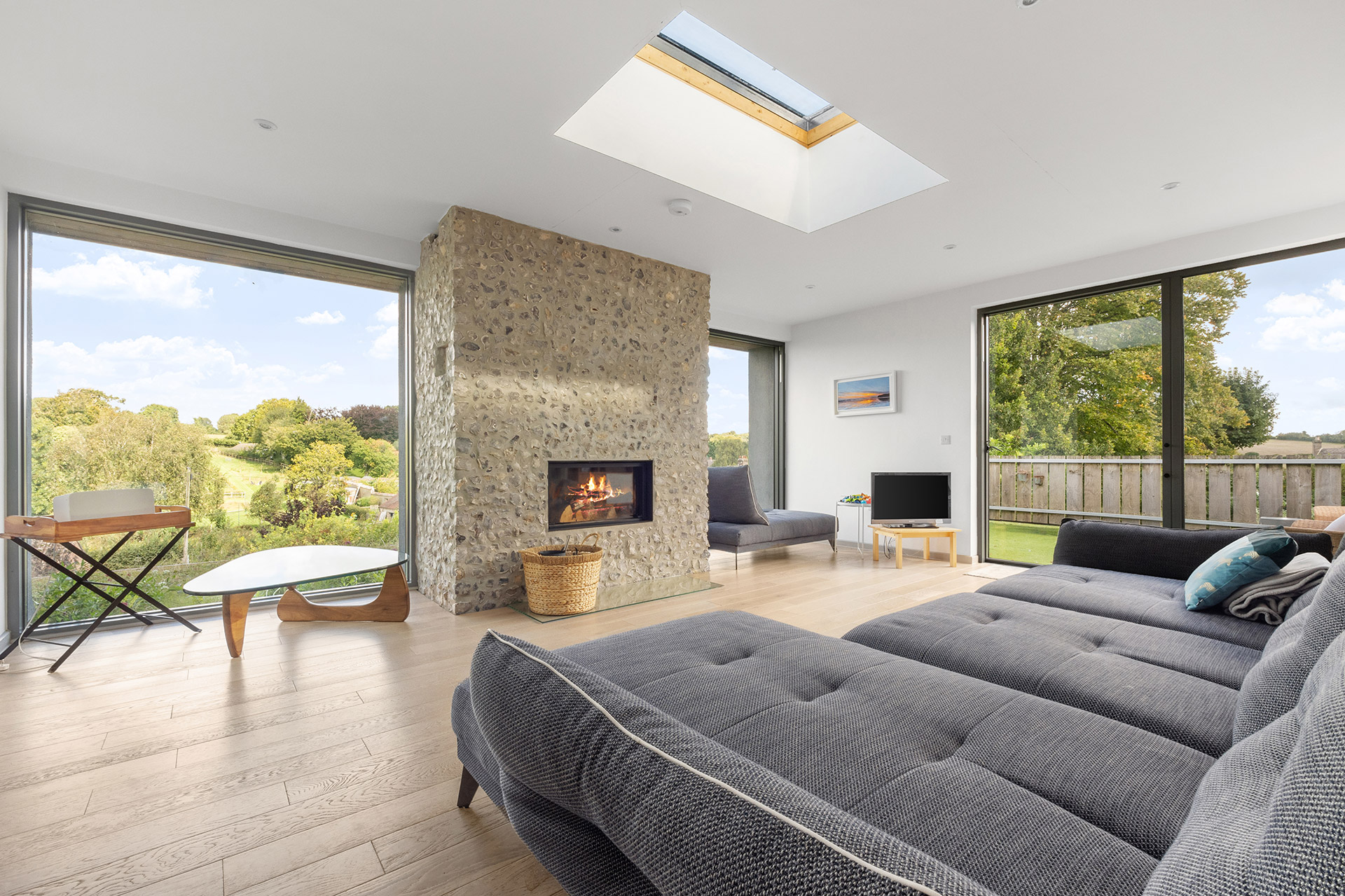 residential modern new home with feature flint fireplace and large windows overlooking countryside