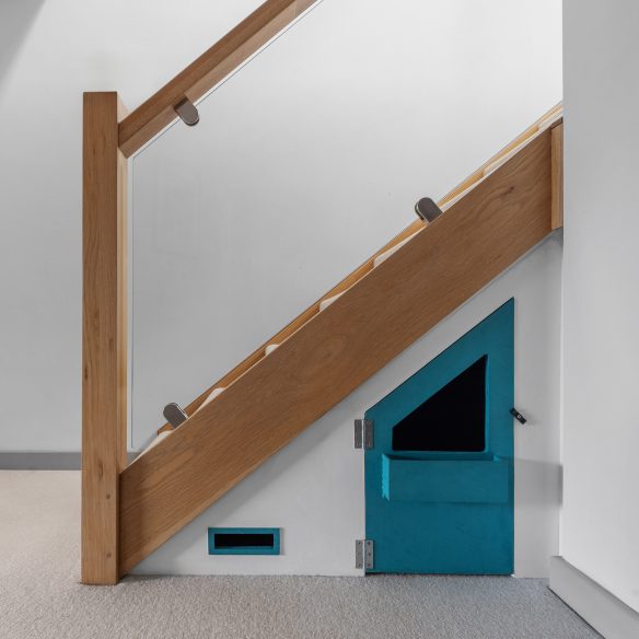 detail view of staircase with glass balustrade and timber hand rail and cupboard under the stairs