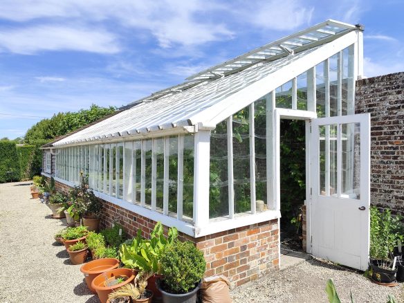 White timber greenhouse over a brick plinth
