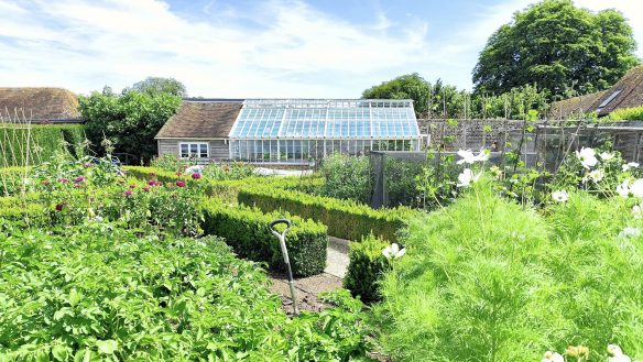 Attractive greenhouse and potting she withing a garden setting