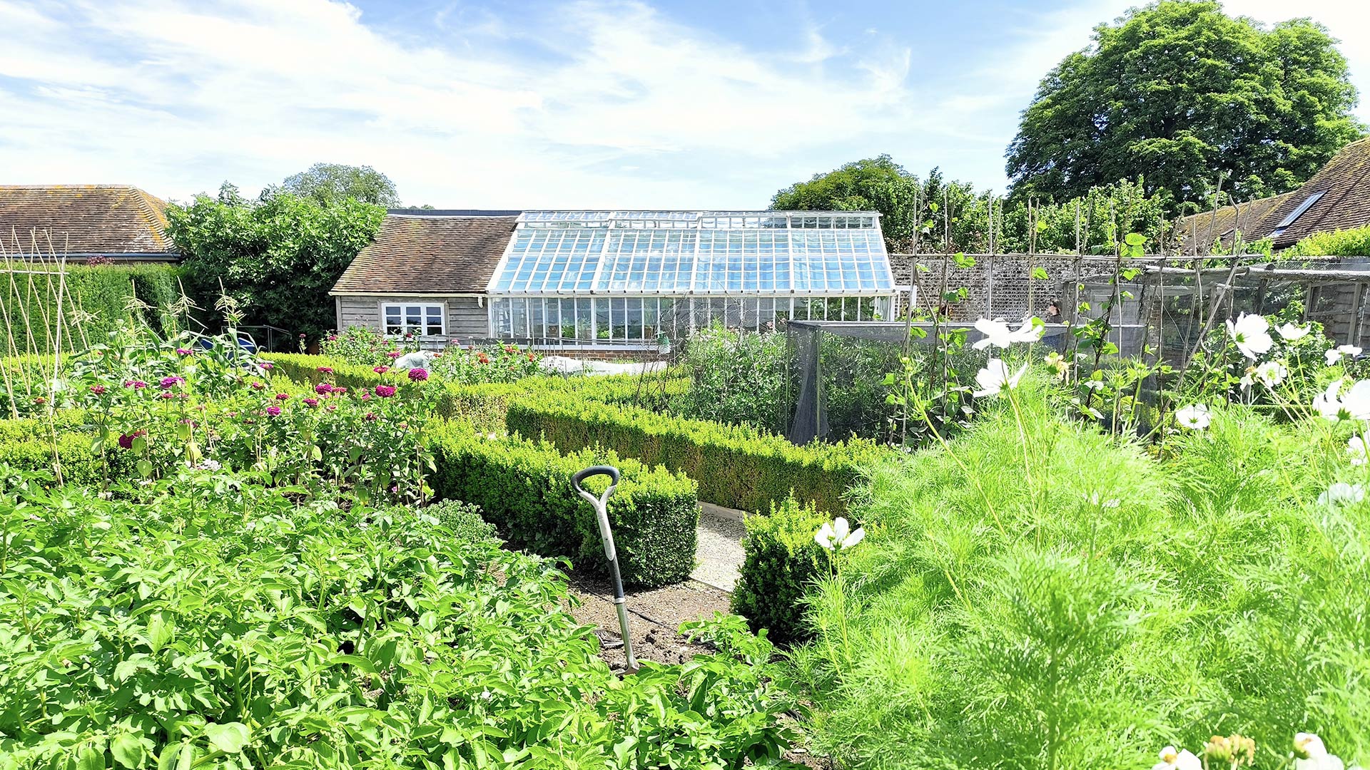 Attractive greenhouse and potting she withing a garden setting