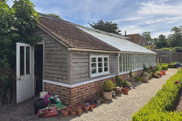 Potting shed and greenhouse building, timber over a brick plinth.